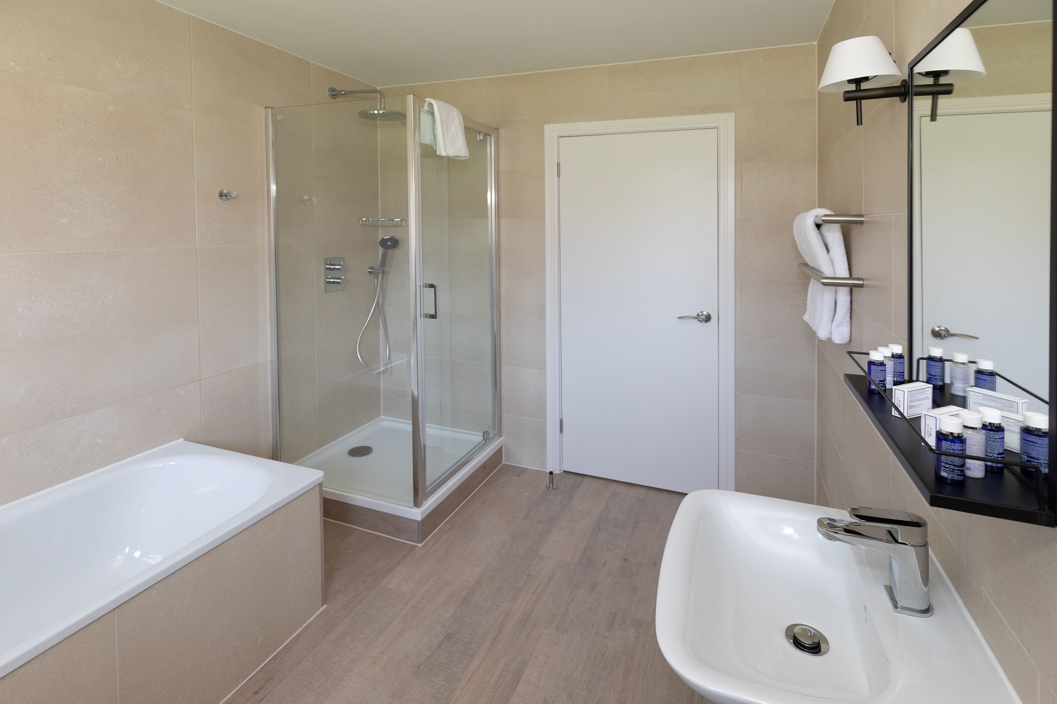A modern bathroom with a glass-enclosed shower, a standalone bathtub, and a sink with a mirror above.