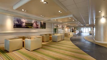 A spacious lobby with a striped carpet, seating area, and artwork on the walls.