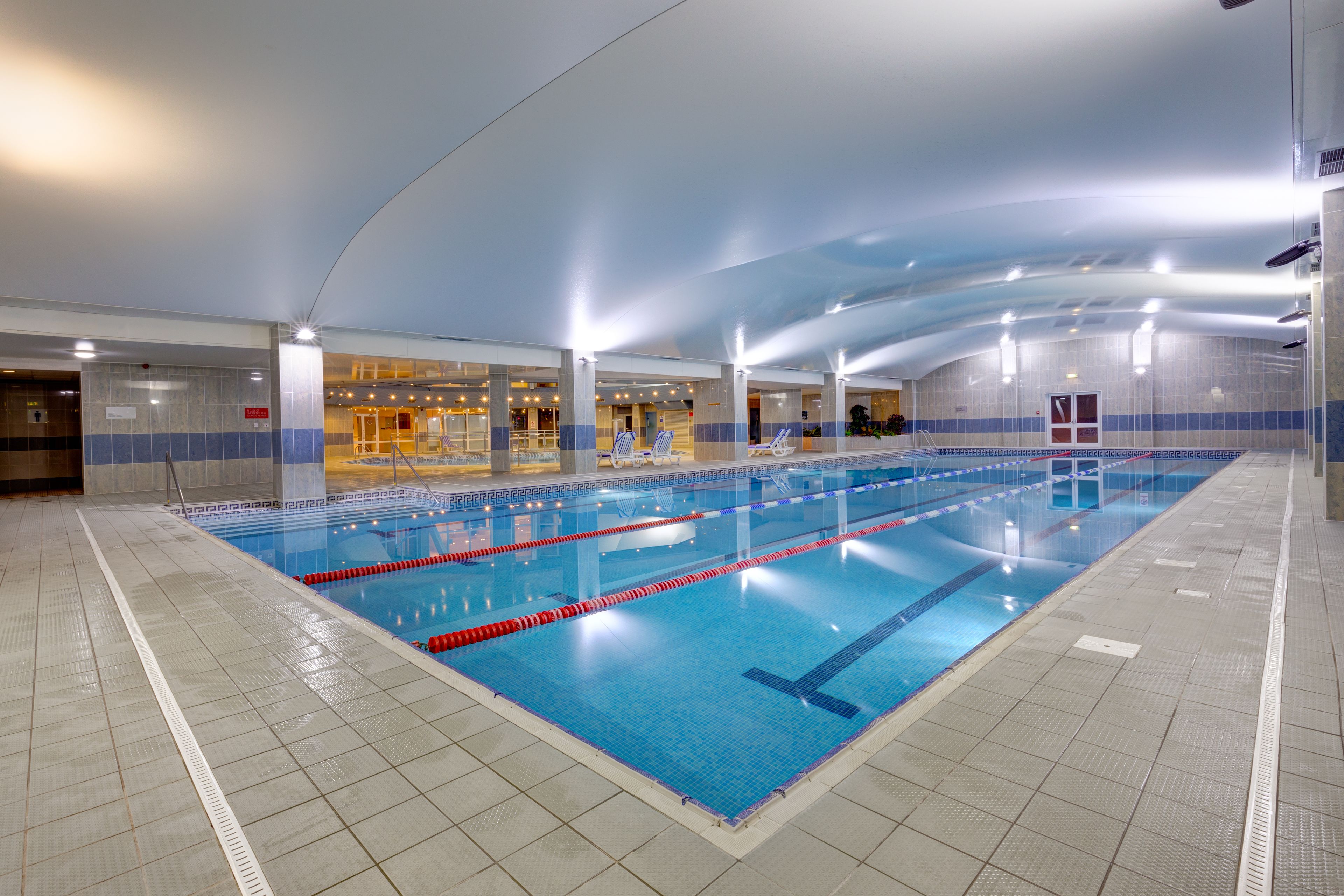 An indoor swimming pool with clear lane markings, tiled walls, and overhead lighting.