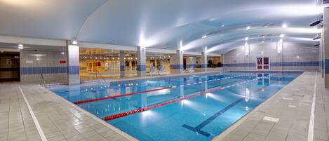 An indoor swimming pool with clear lane markings, tiled walls, and overhead lighting.