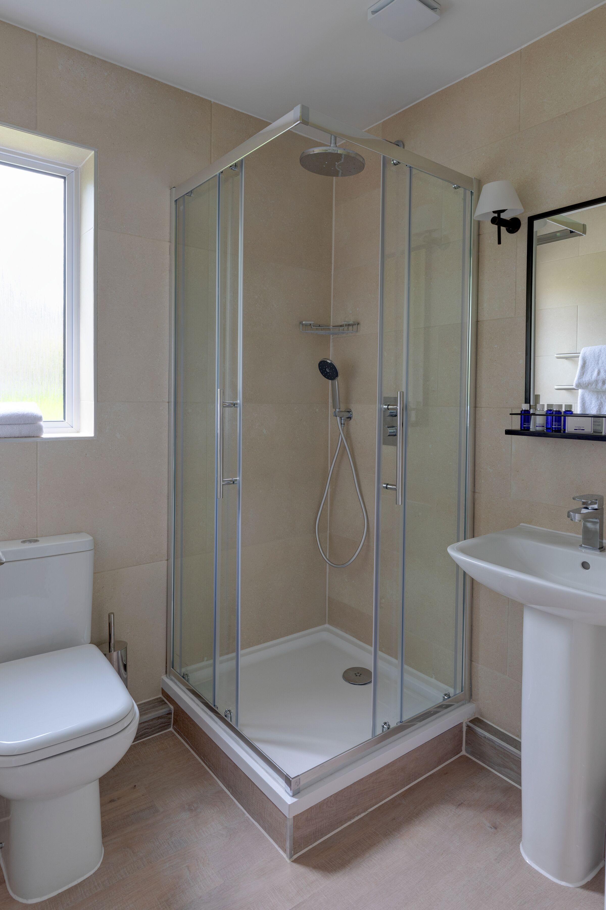 A modern bathroom with a glass-enclosed shower, a white toilet, and a sink.