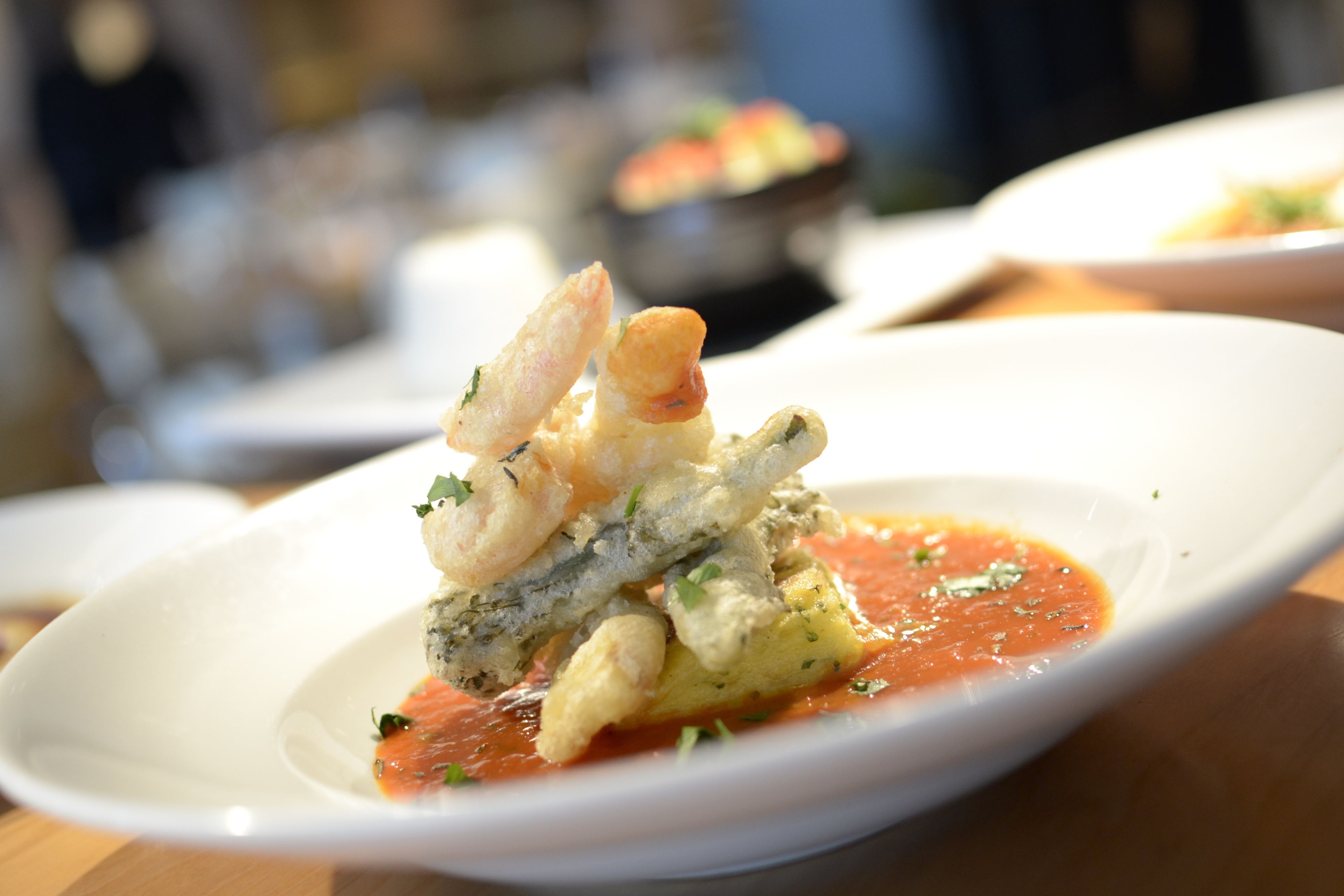 A white plate with a seafood dish, possibly shrimp, on a wooden table.