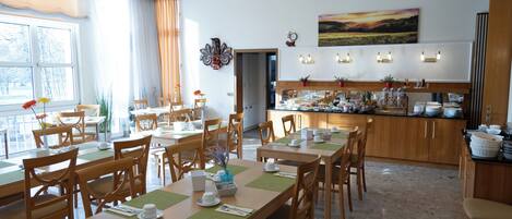 Un comedor de hotel con varias mesas, sillas y una barra de buffet.