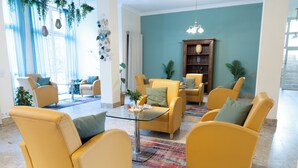 A living room with yellow sofas, a glass coffee table, and a bookshelf. - Hotel Haus am Park (Bad Homburg v.d. Hoehe)