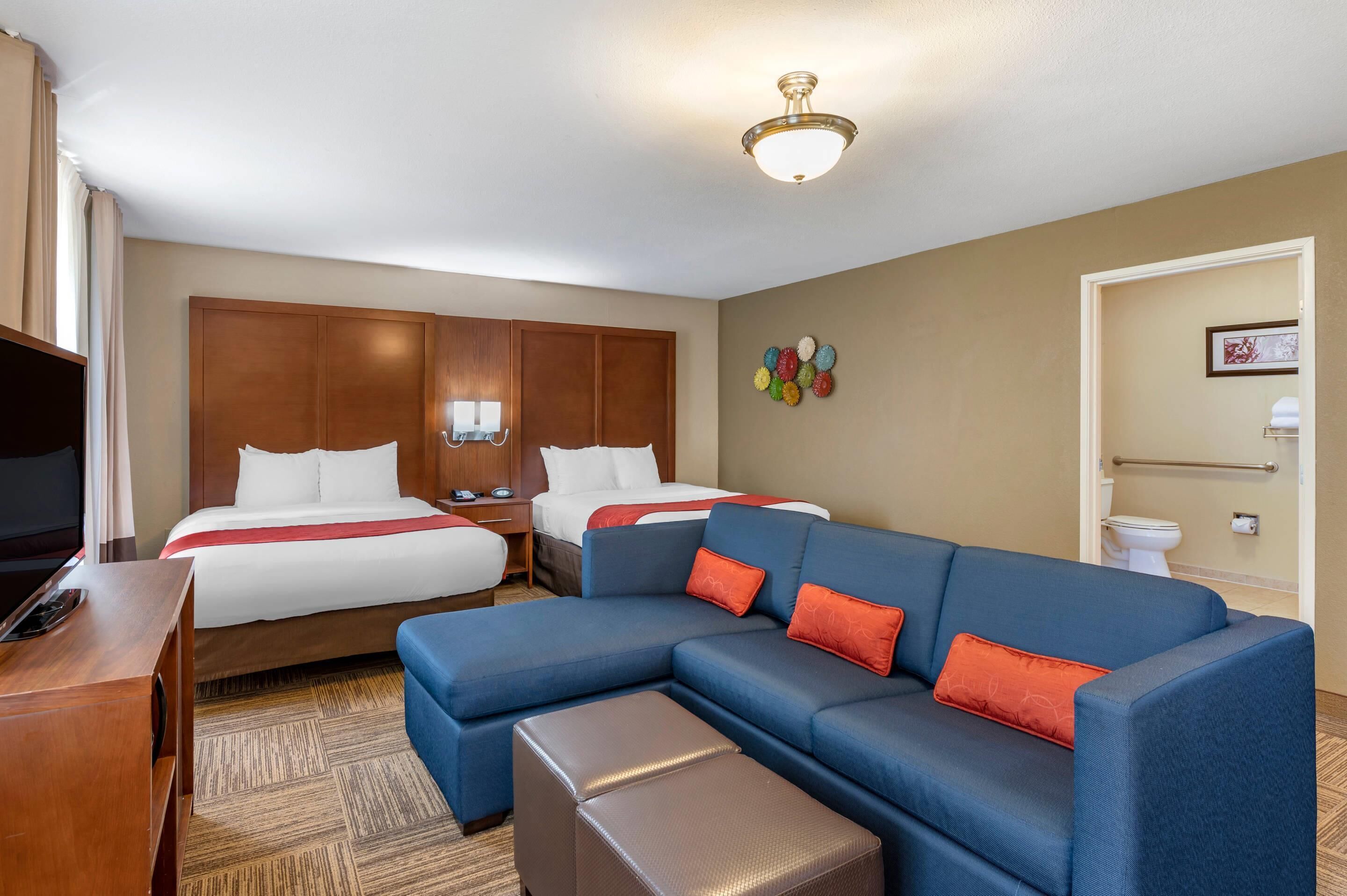 Habitación de hotel con dos camas, un sofá, un televisor y un baño.