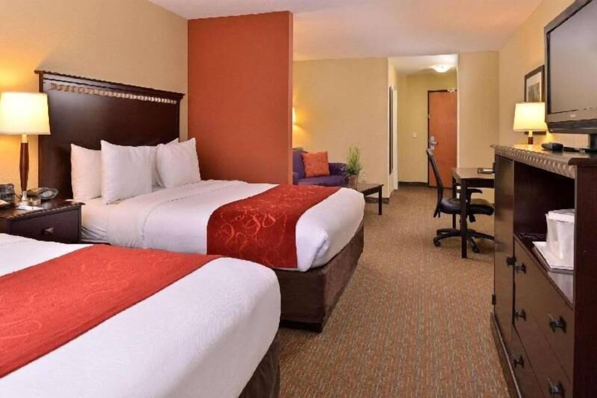 Une chambre d’hôtel avec deux lits, un bureau, une chaise, une télévision et une armoire.
