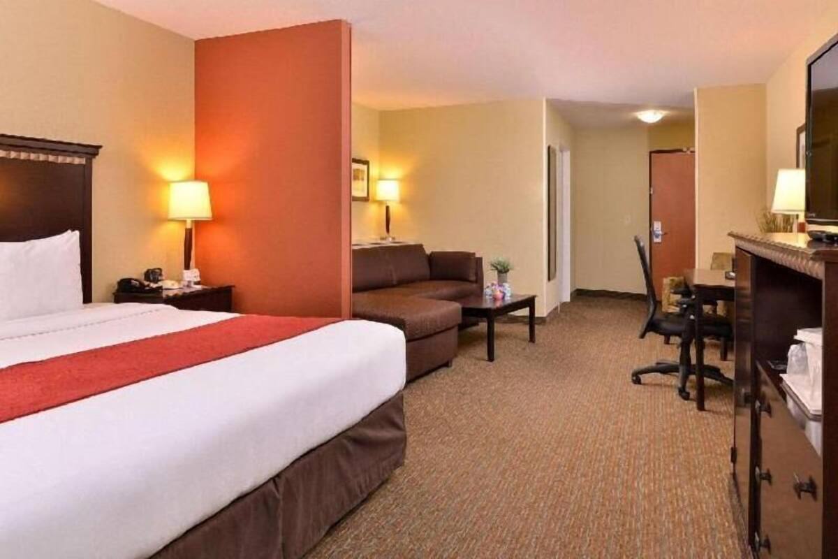 Une chambre d’hôtel avec un lit, un canapé, un bureau et une télévision.
