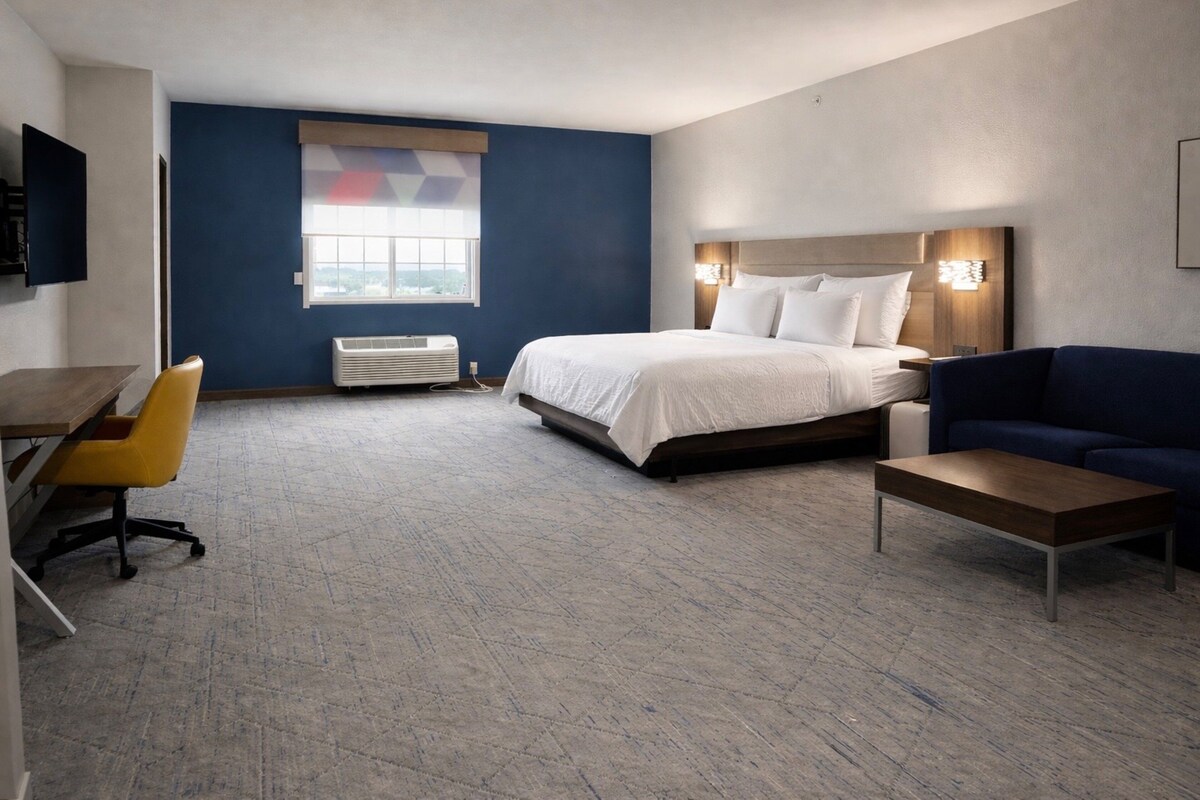A hotel room with a bed, a sofa, a desk, and a chair.