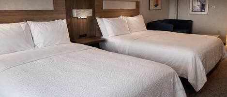 Une chambre d’hôtel avec deux lits, une table de chevet, une lampe et des œuvres d’art accrochées aux murs.