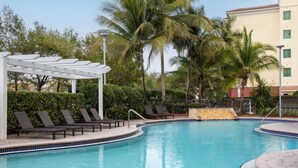A swimming pool with lounge chairs, a covered seating area, and palm trees. - Hampton Inn & Suites Homestead Miami South (Homestead)