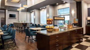 A hotel dining area with a central island, blue chairs, and a breakfast sign. - Hampton Inn & Suites Homestead Miami South (Homestead)