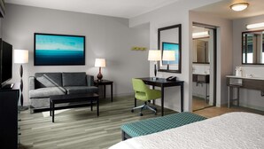 A hotel room with a bed, a sofa, a desk, a chair, a TV, and a bathroom visible through an open door. - Hampton Inn & Suites Homestead Miami South (Homestead)