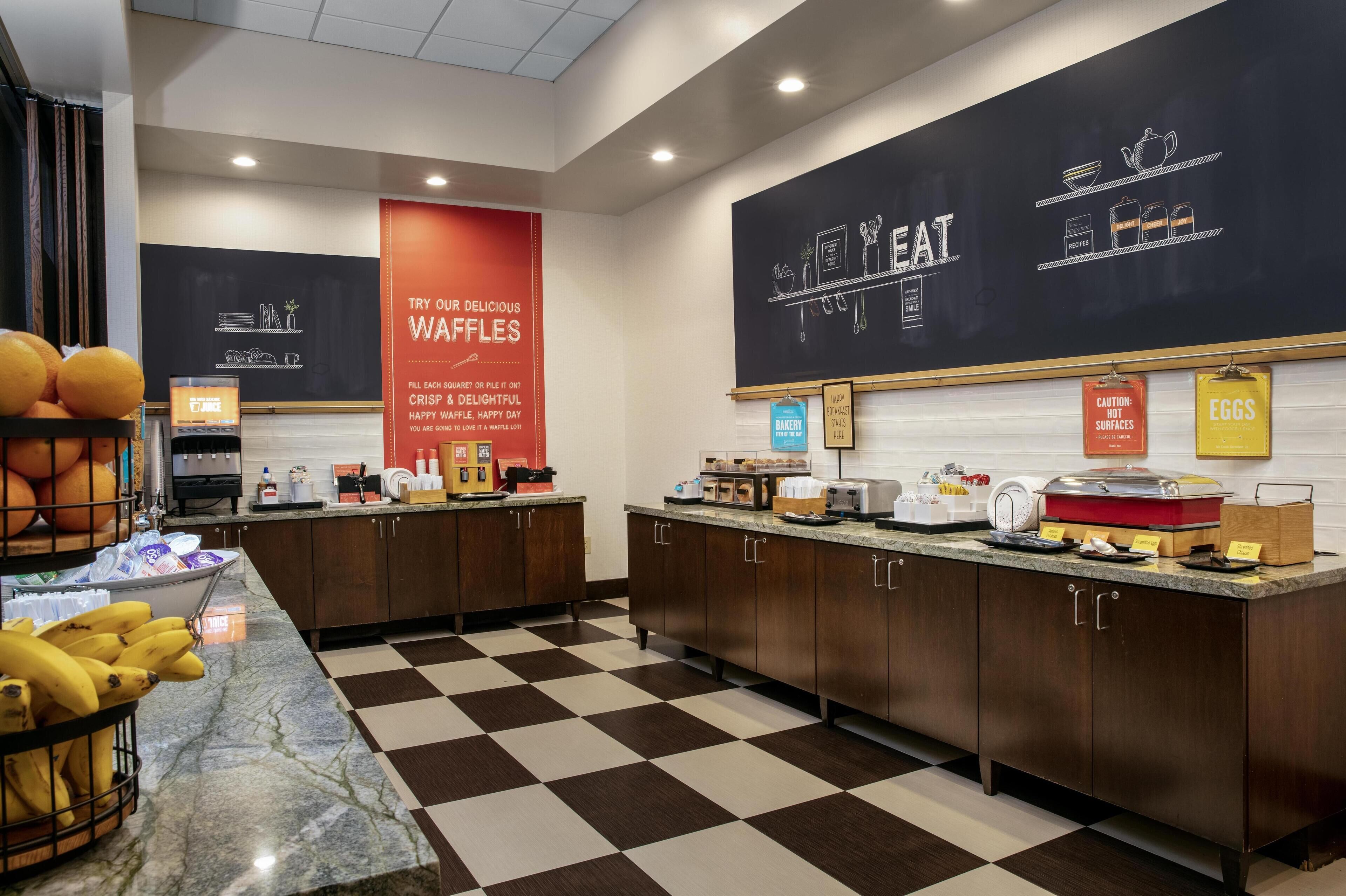 Un espace cuisine équipé de postes pour préparer des gaufres, d’un tableau noir servant de menu et de divers appareils de cuisine.