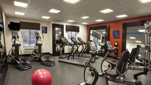 Ein Fitnessstudio mit Laufbändern, Crosstrainern und einem roten Trainingsball.