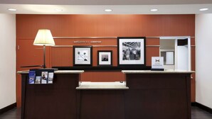 Ein Empfangsschalter mit einem Schild 'Welcome to Conroe', gerahmten Fotos und einem 'Hilton Honors'-Schild.