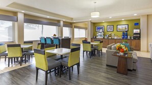 Een hotellobby met zithoeken, een receptiebalie en een kitchenette.