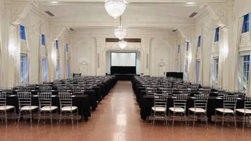 A large, ornate hall with rows of chairs and a stage at the front.