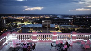 A rooftop patio with tables and chairs, overlooking a cityscape with a business center in the background. - The Mayo Hotel (Tulsa)