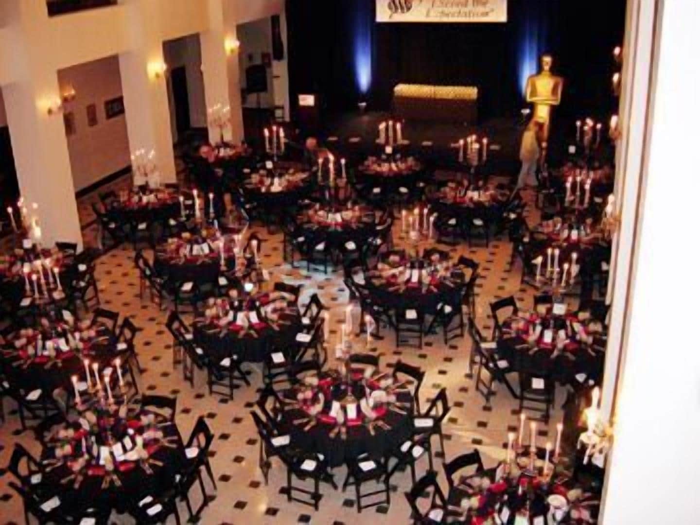 A banquet hall with multiple round tables arranged in a circular pattern, each with chairs and candles.