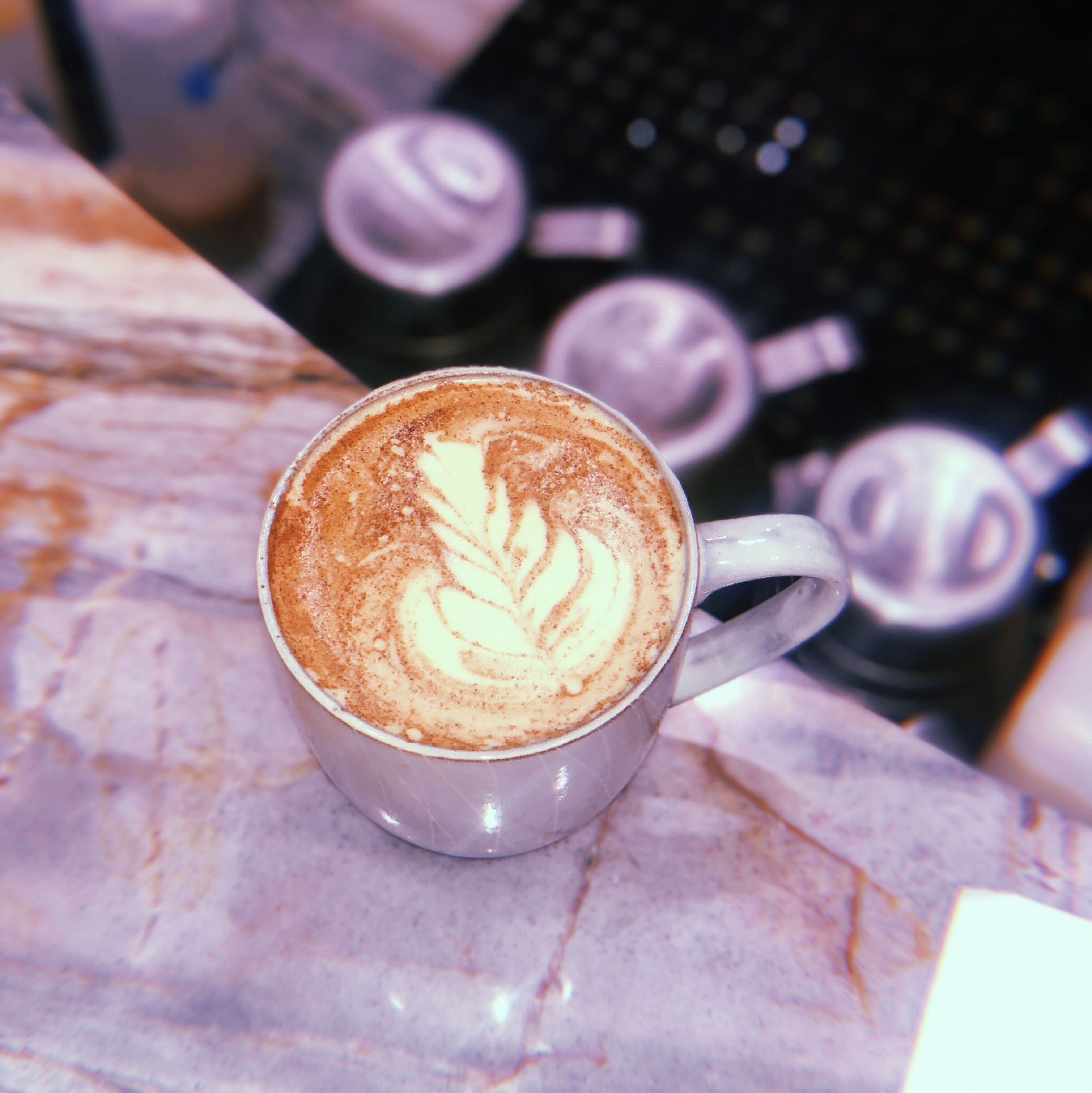 Una tassa de cafè amb dibuixos en escuma sobre una superfície de marbre.