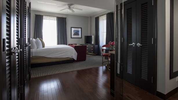 A hotel room with a bed, a desk, a chair, a TV, and a wardrobe. - The Mayo Hotel (Tulsa)