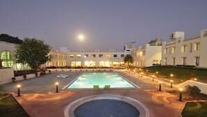 A hotel courtyard with a swimming pool, lounge chairs, and a well-lit walkway. - Inder Residency Resort & Spa Udaipur (Udaipur)