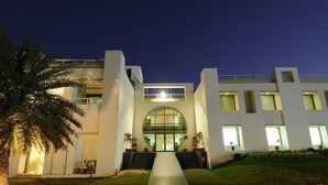 A modern building with a central entrance, a staircase leading up to the entrance, and a well-lit pathway. - Inder Residency Resort & Spa Udaipur (Udaipur)