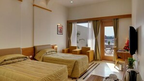 A hotel room with two beds, a dining area, a TV, and a balcony with a view. - Inder Residency Resort & Spa Udaipur (Udaipur)