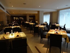 A hotel dining area with multiple tables and chairs, arranged in a spacious layout. - Minerva Grand Banjara Hills (Hyderabad)