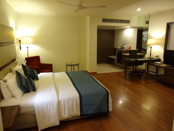 A hotel room with a bed, a desk, a chair, a television, and a mirror. - Minerva Grand Banjara Hills (Hyderabad)