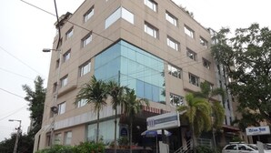 A multi-story hotel with a glass facade, a boutique hotel sign, and a parking area with a car. - Minerva Grand Banjara Hills (Hyderabad)