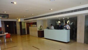 A hotel lobby with a reception desk, a red chair, and a Buddha statue. - Minerva Grand Banjara Hills (Hyderabad)