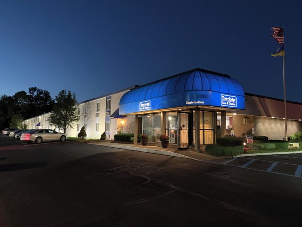 A Travelodge Inn & Suites with a registration area, parking lot, and a flagpole with flags.
