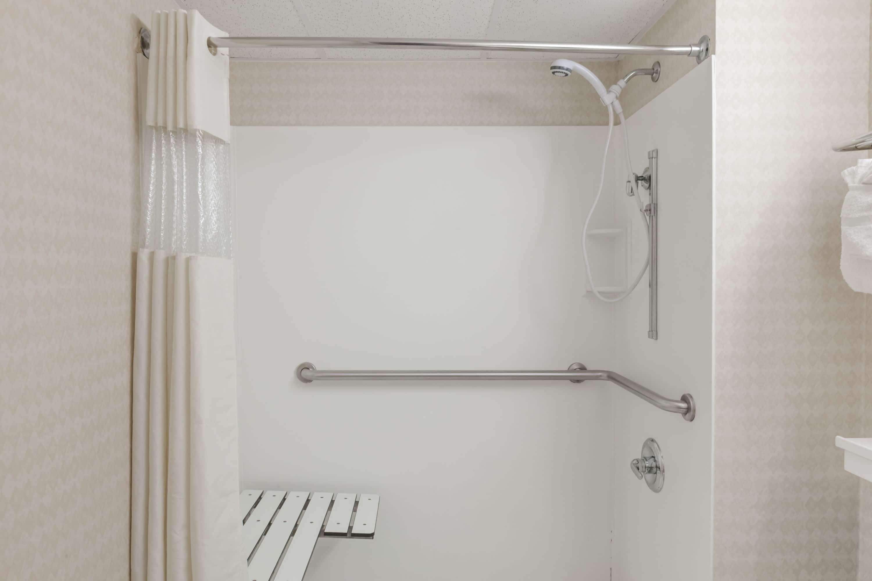 Un espace douche équipé d’une barre d’appui, d’un porte-serviettes et d’un pommeau de douche.
