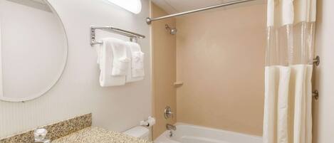 Un baño con lavamanos, espejo, toallero, ducha y bañera.