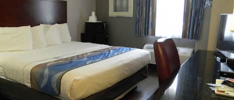 Hotelkamer met een bed, bureau, stoel, televisietoestel en een raam met gordijnen.