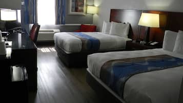 A hotel room with two beds, a desk with a chair, a TV, and a lamp.