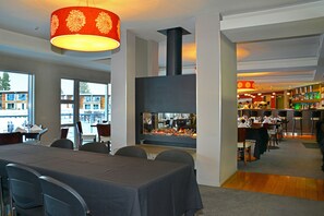 A modern dining area with a fireplace, large windows, and a bar/lounge area. - Peppers Bluewater Resort (Lake Tekapo)