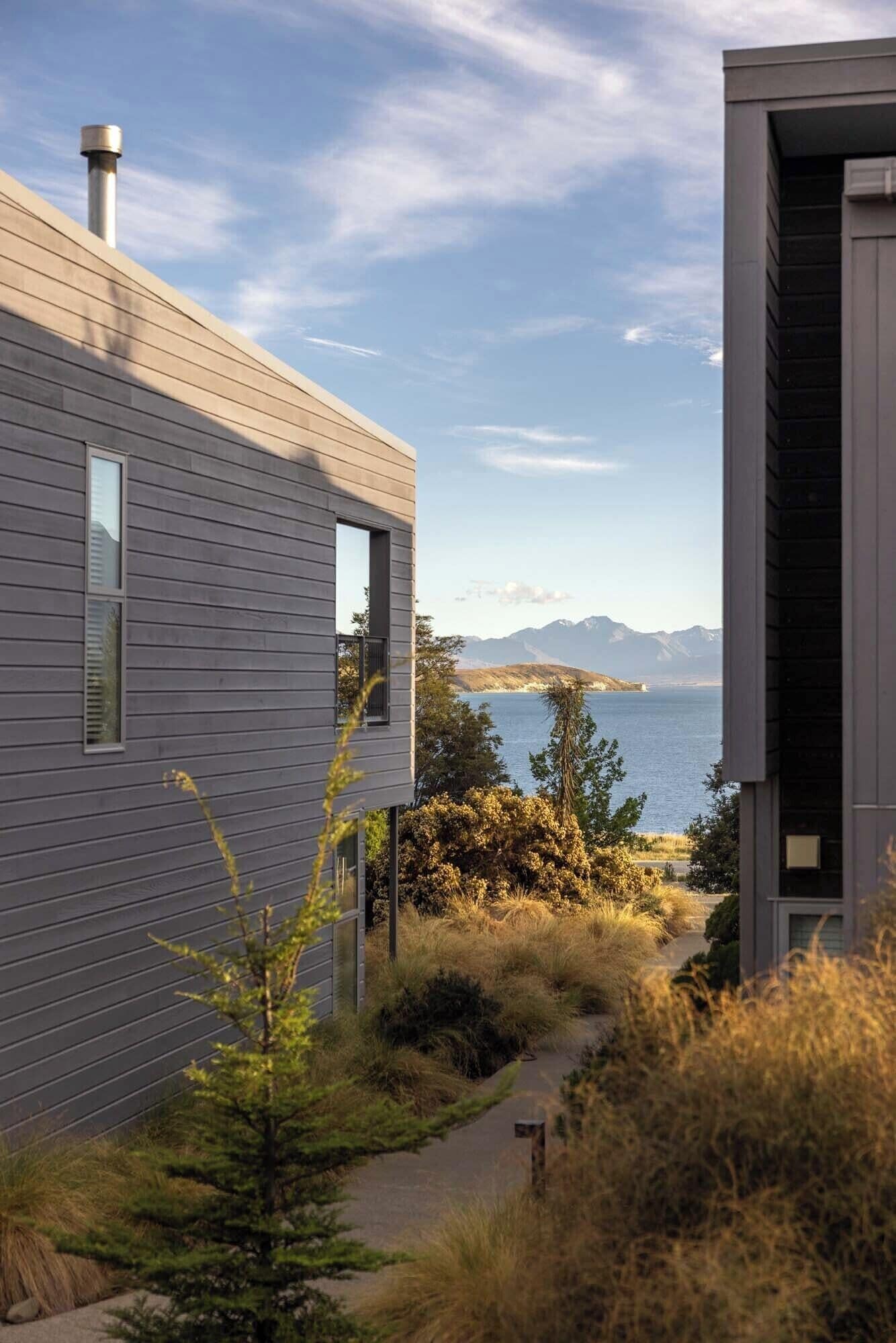 A modern house with a view of a lake and mountains.