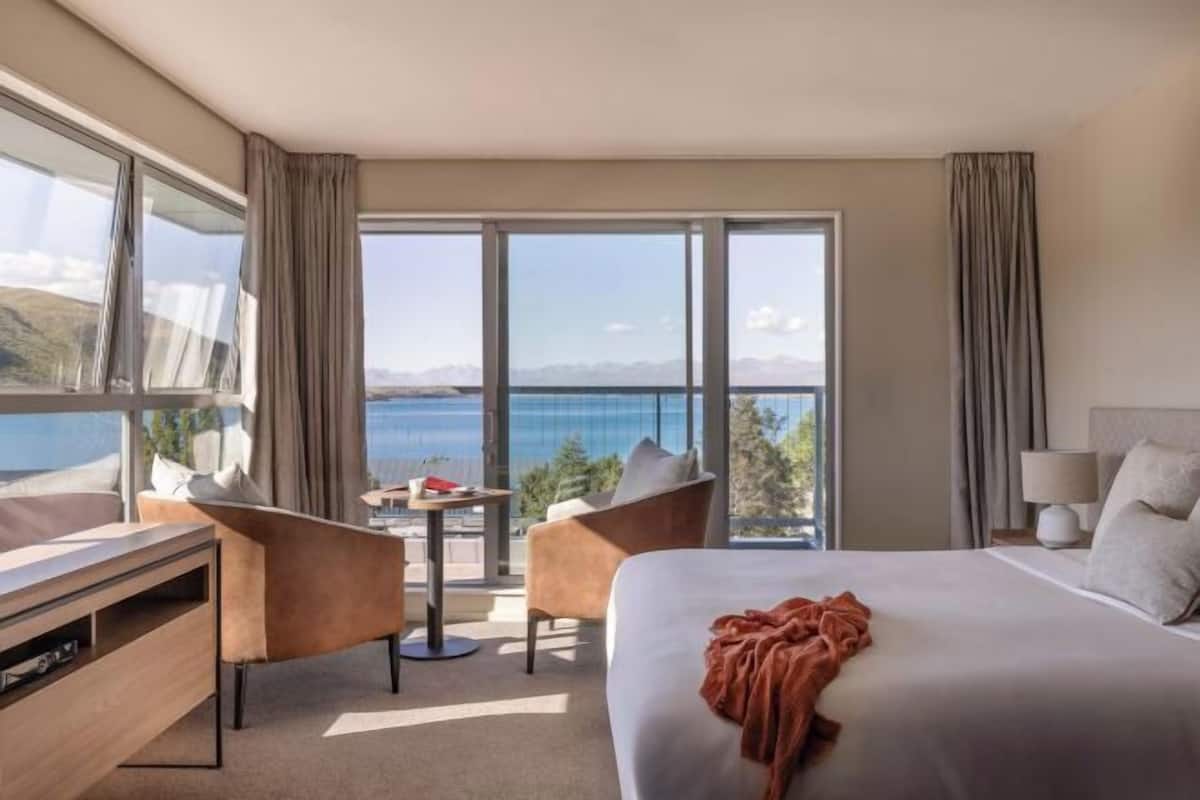 Habitación de hotel con una cama grande, un escritorio, una silla y vistas al mar.