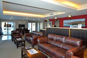 A lobby with leather sofas, a reception desk, and a large window with a mountain view.