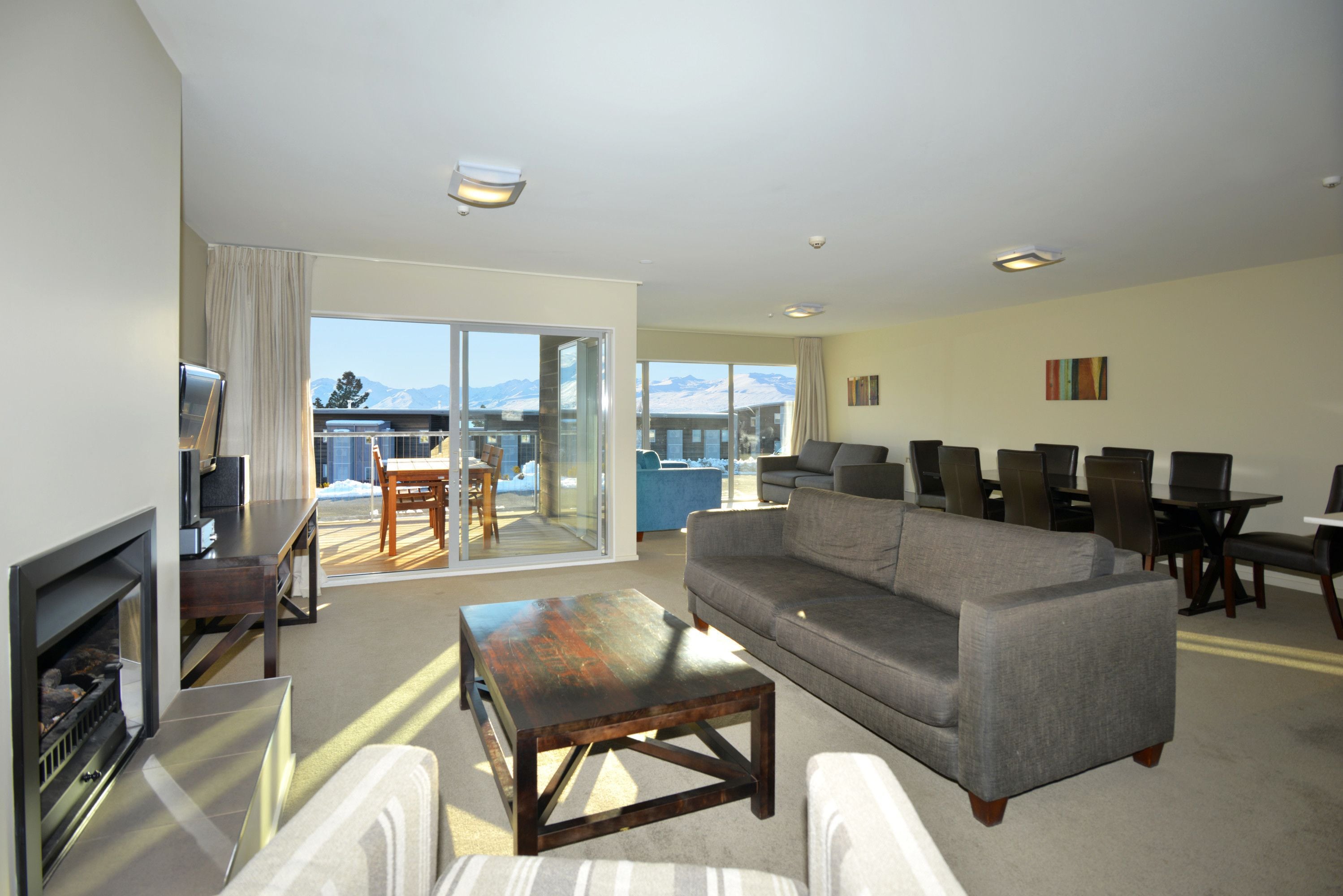 A spacious living room with a fireplace, a sofa, and a dining area with chairs and a table.