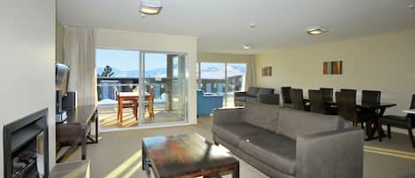 A spacious living room with a fireplace, a sofa, and a dining area with chairs and a table.