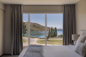 A bedroom with a large window, a bed, and a nightstand. - Peppers Bluewater Resort (Lake Tekapo)