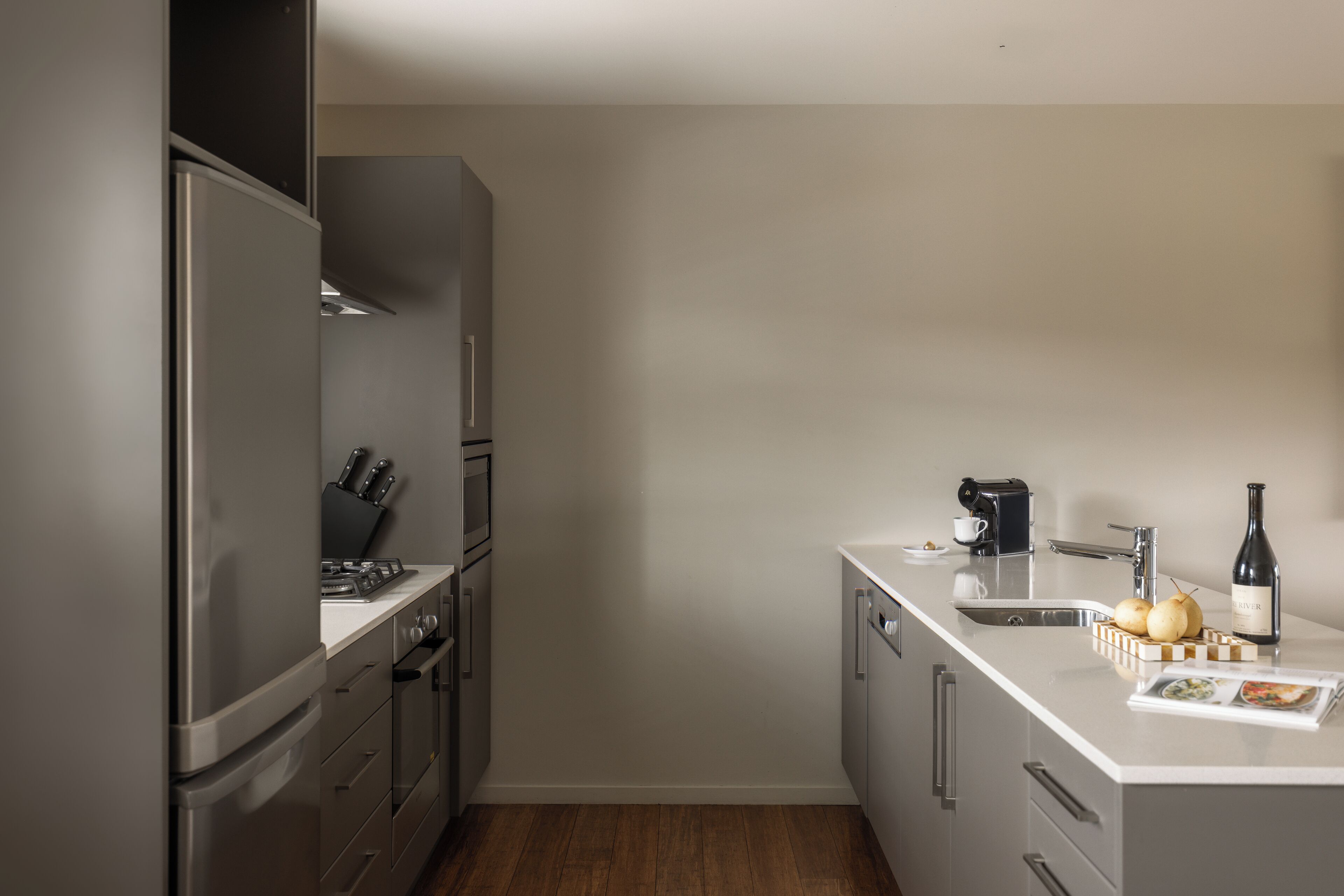 A compact kitchen with a refrigerator, stove, sink, and a coffee maker.
