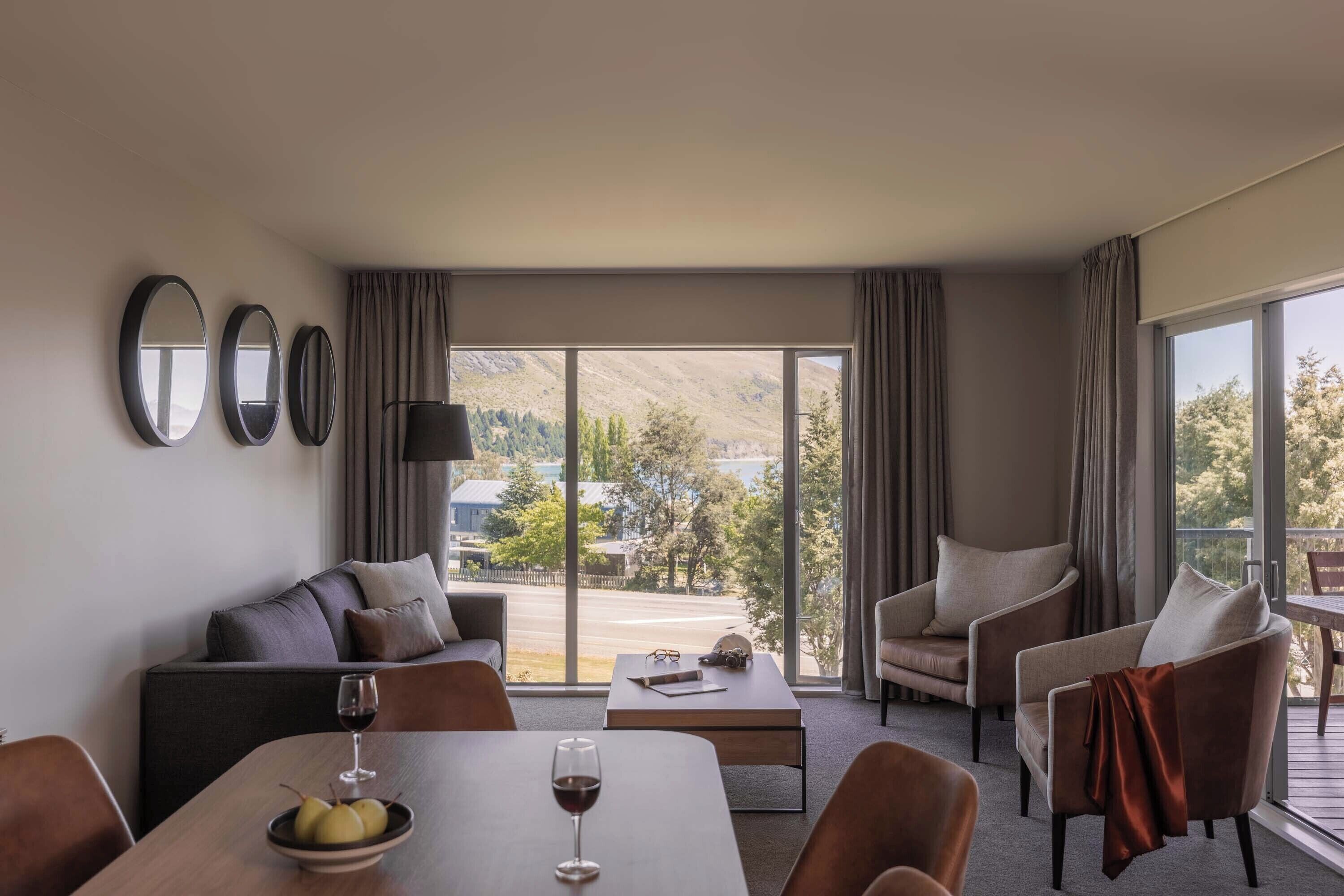 Een moderne hotelkamer met balkon, een zithoek, een eettafel en uitzicht op het landschap.