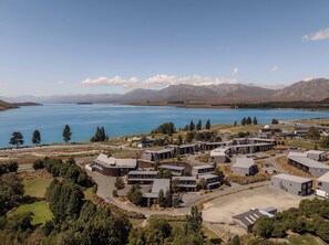 A modern hotel complex with contemporary architecture, situated near a large lake with mountains in the background. - Peppers Bluewater Resort (Lake Tekapo)