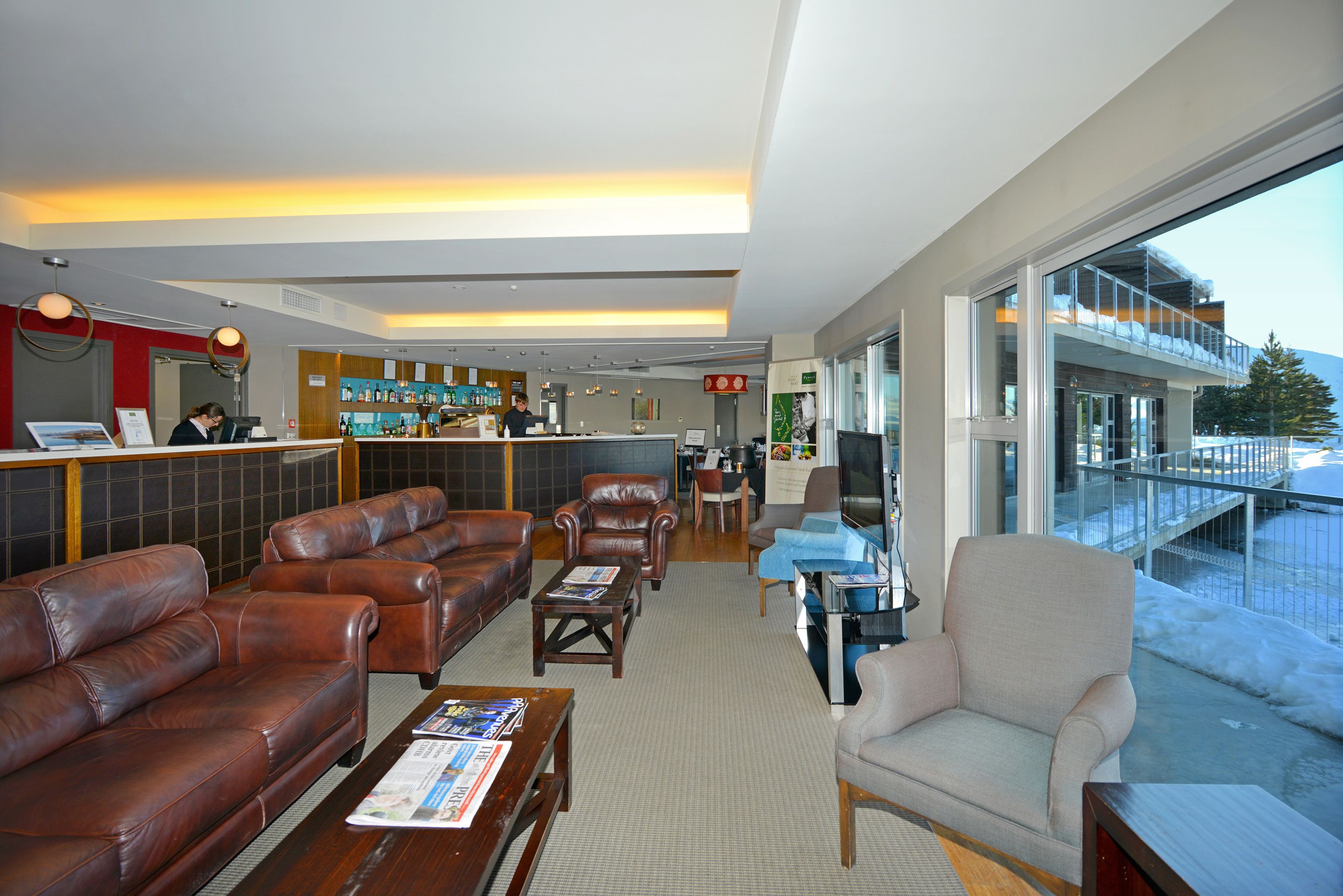 A hotel lobby with leather sofas, a bar area, and a view of the outside.