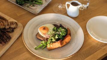 A plate of food with a poached egg, broccoli, and a piece of meat on a wooden table.
