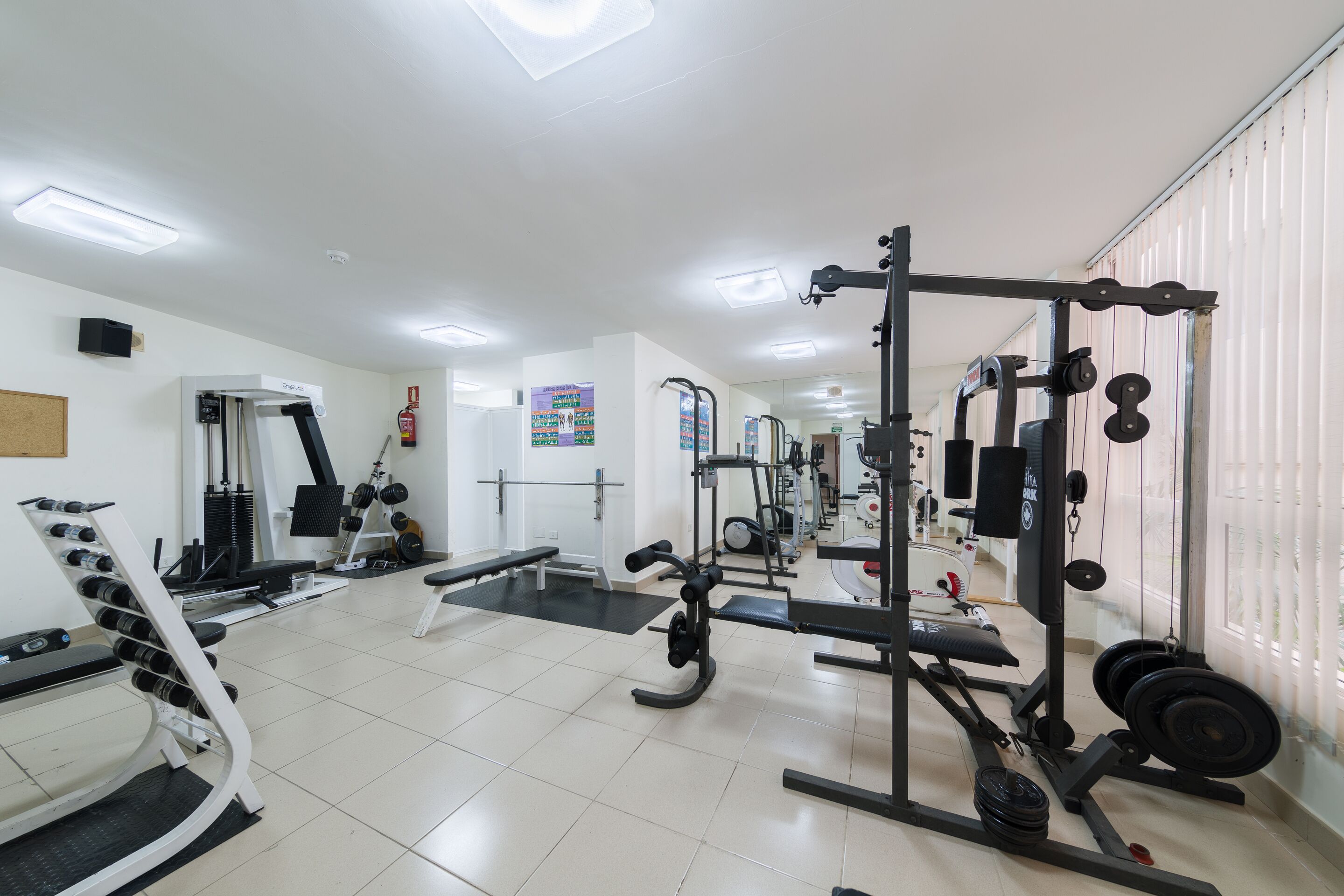 A gym with various exercise equipment, including treadmills, weight machines, and free weights.